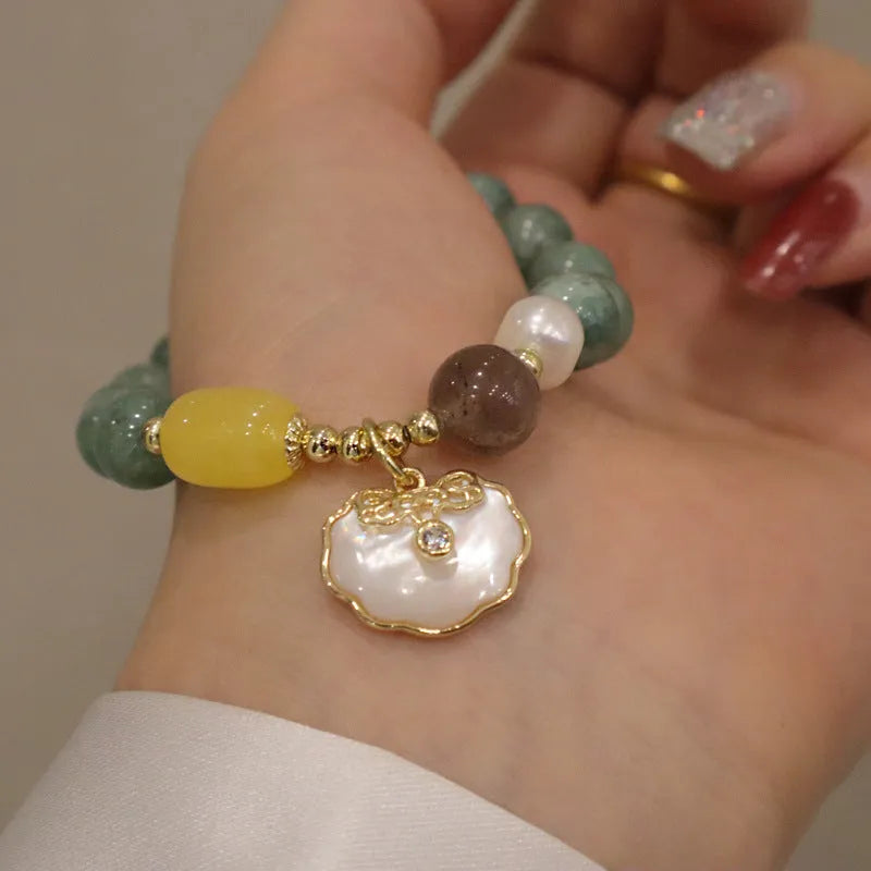 Green jade shell bracelet for women on a wrist, showing the natural stone colour and shell design detail.