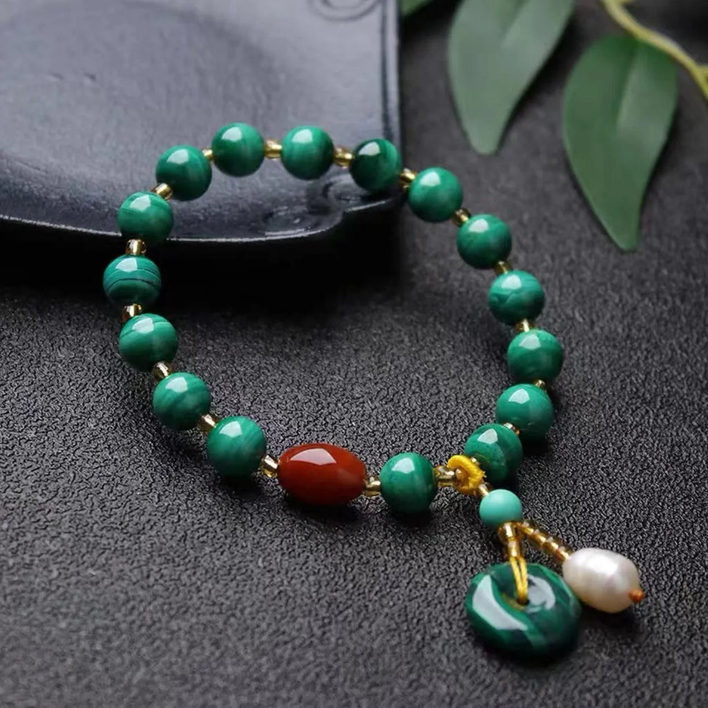 Handmade natural malachite and red agate stone bead bracelet on a wrist.