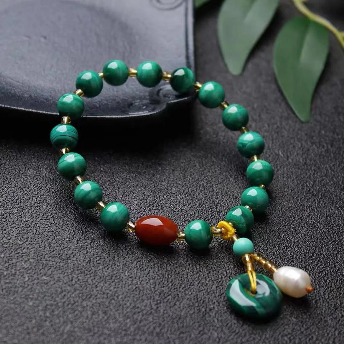 Handmade natural malachite and red agate stone bead bracelet on a wrist.