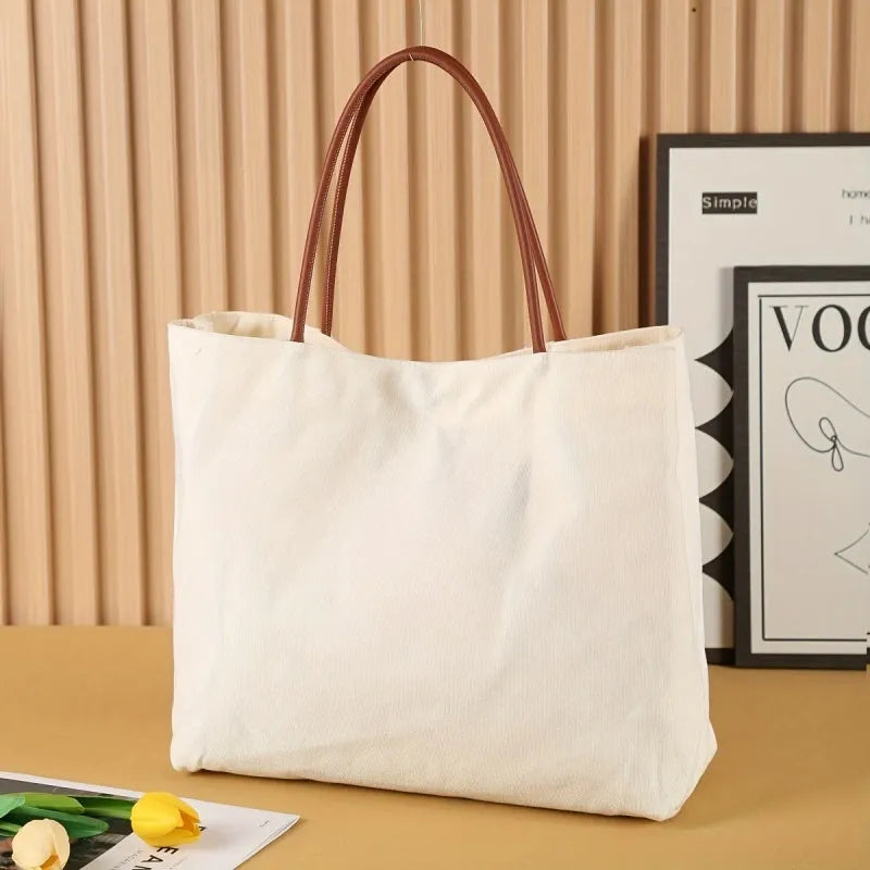 Beige white and white canvas tote bag with long handle straps.