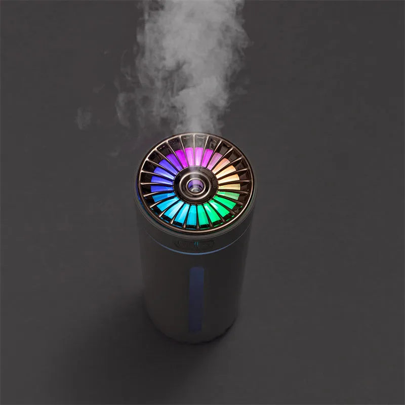 Black wireless ultrasonic humidifier with colourful lights, shown next to a USB cable on a desk.