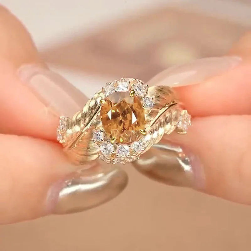 Gold-coloured women's ring with embossed feather pattern and yellow zircon gemstone