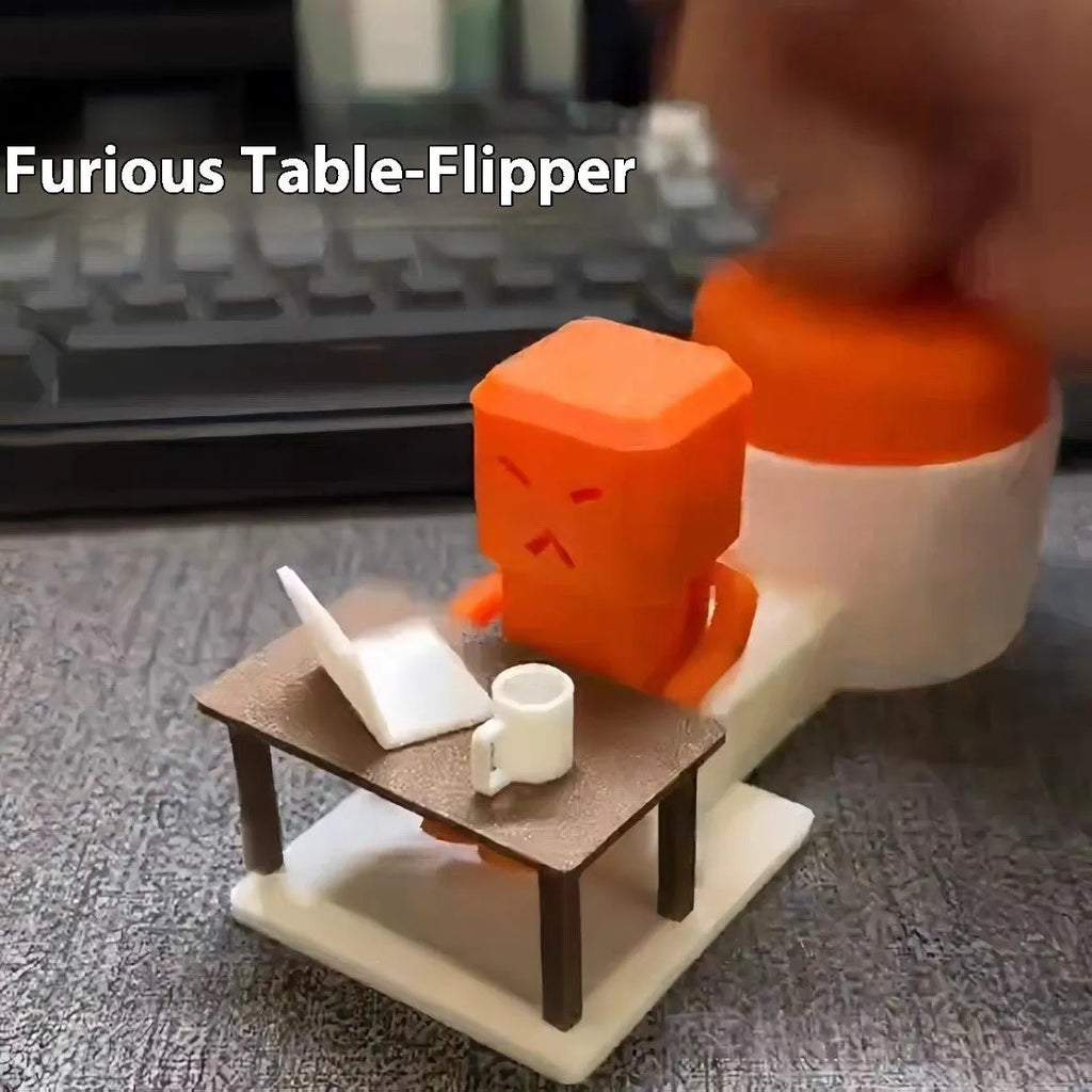 Orange plastic table-turning decompression toy measuring 16cm long on a desk