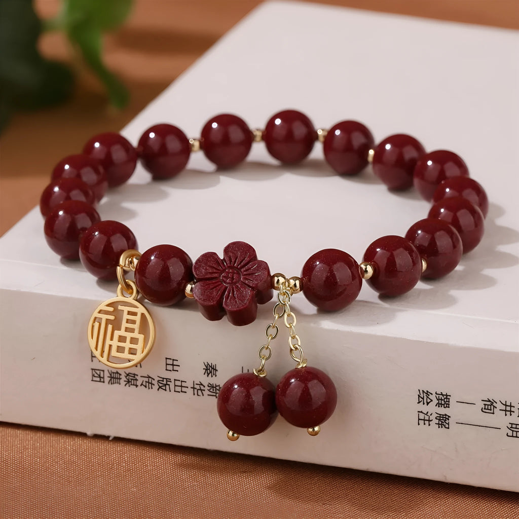 Women's cinnabar bracelet with purple gold sand finish and traditional fu character charm with tassel detailing